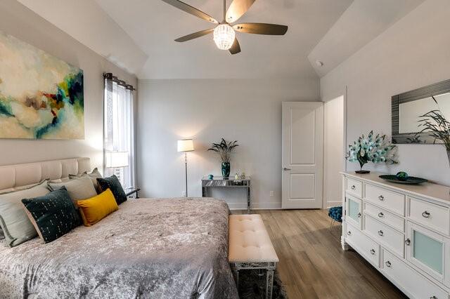 bedroom with ceiling fan, vaulted ceiling, and hardwood / wood-style floors