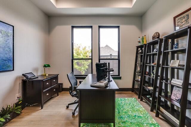 office space with a raised ceiling and light wood-type flooring