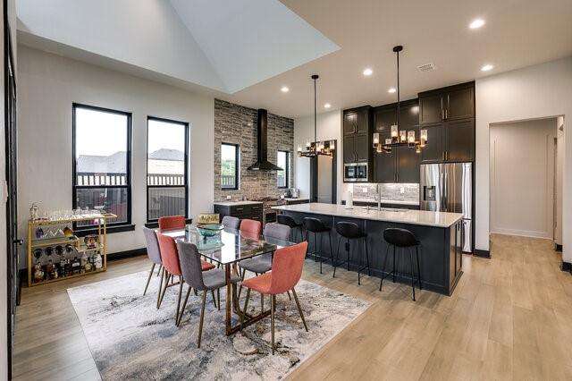 dining area featuring high vaulted ceiling, light hardwood / wood-style flooring, a wood stove, and sink