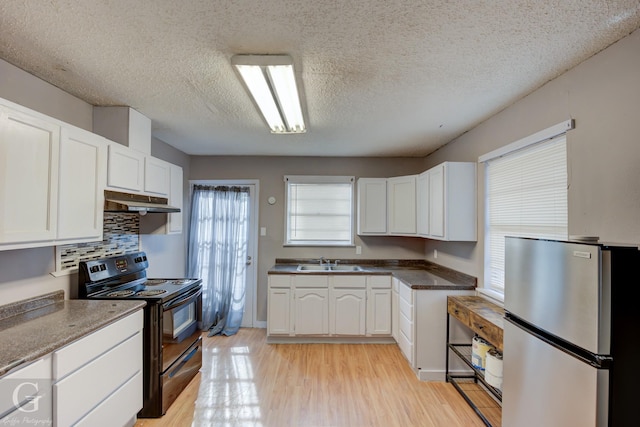 kitchen featuring sink, stainless steel fridge, white cabinetry, and black / electric stove