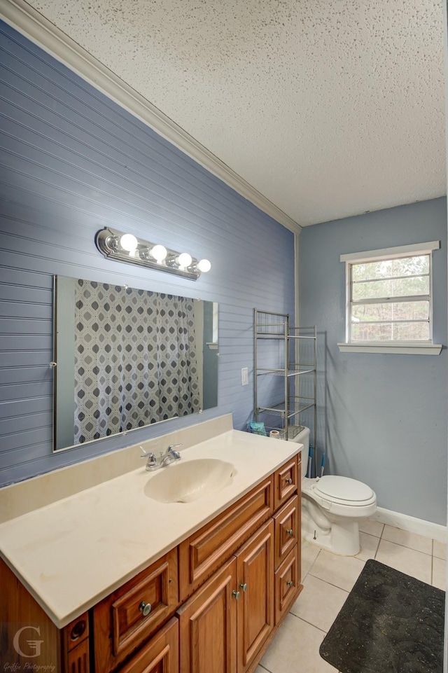 bathroom with toilet, vanity, tile patterned floors, wooden walls, and a textured ceiling