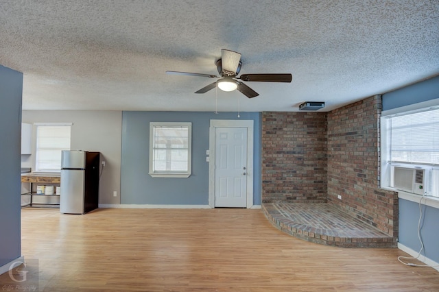 unfurnished living room with cooling unit, a healthy amount of sunlight, and light hardwood / wood-style flooring