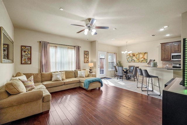 living room featuring ceiling fan with notable chandelier and light hardwood / wood-style flooring