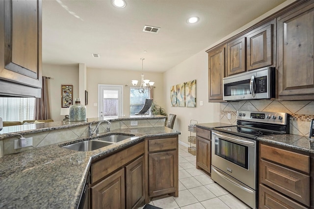 kitchen featuring appliances with stainless steel finishes, decorative backsplash, sink, a notable chandelier, and light tile patterned flooring