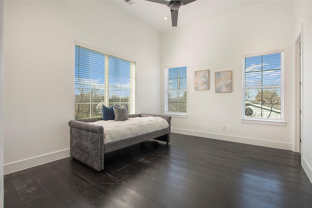 bedroom with ceiling fan, dark wood-type flooring, and a towering ceiling