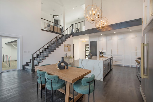 dining space featuring sink, dark hardwood / wood-style flooring, a towering ceiling, and ceiling fan with notable chandelier