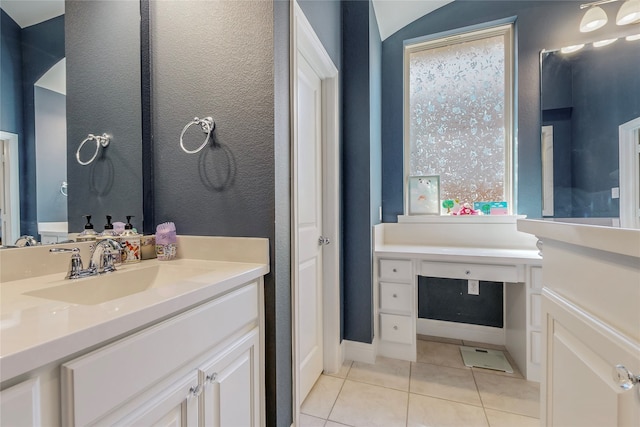 bathroom with tile patterned flooring, vaulted ceiling, and vanity