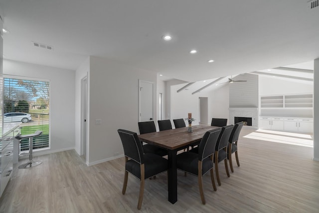 dining area featuring a brick fireplace, light hardwood / wood-style floors, and ceiling fan