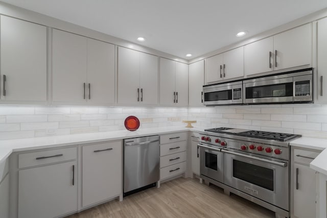 kitchen with white cabinetry, stainless steel appliances, decorative backsplash, and light hardwood / wood-style flooring