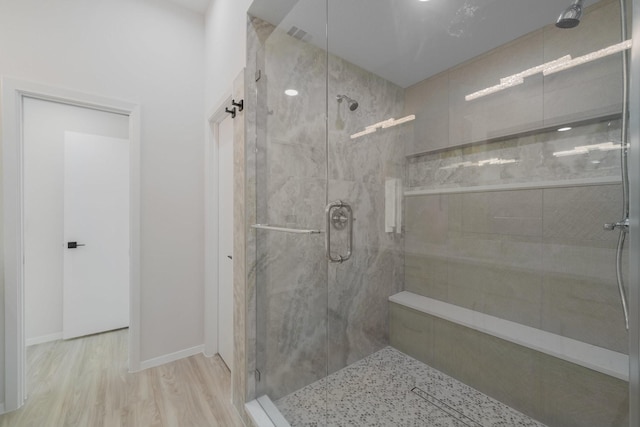 bathroom with a shower with shower door and hardwood / wood-style floors