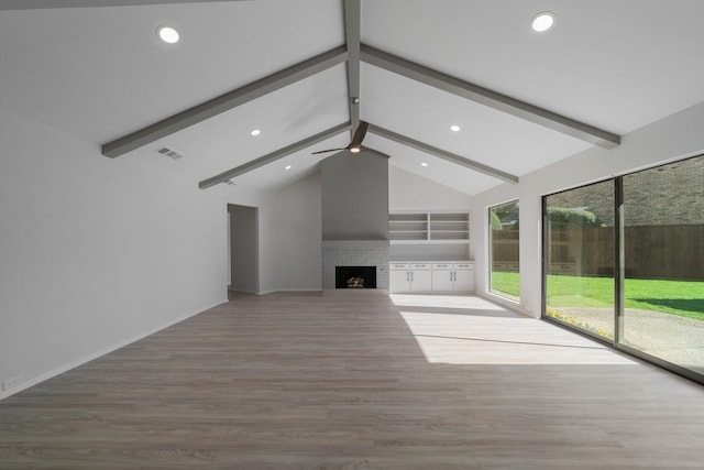 unfurnished living room with wood-type flooring, beamed ceiling, ceiling fan, high vaulted ceiling, and a brick fireplace