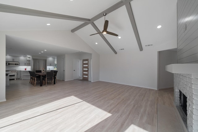 living room with a brick fireplace, ceiling fan, light hardwood / wood-style flooring, and beamed ceiling