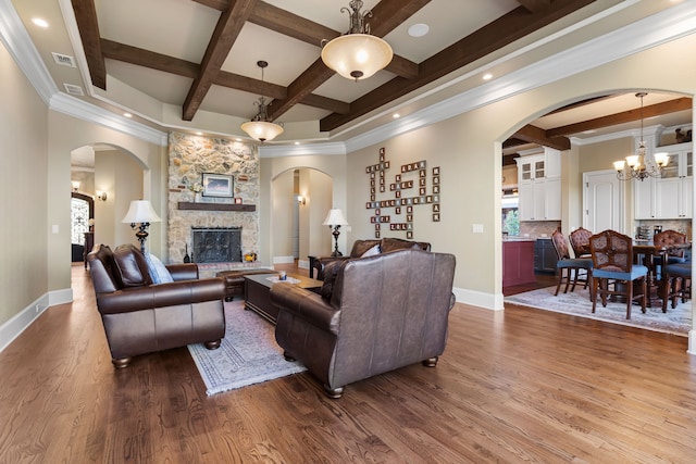 living room with a fireplace, beamed ceiling, wood-type flooring, coffered ceiling, and a chandelier