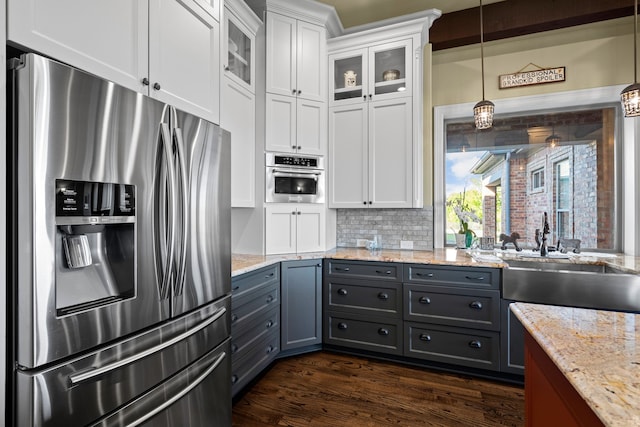 kitchen with appliances with stainless steel finishes, hanging light fixtures, dark wood-type flooring, white cabinets, and sink