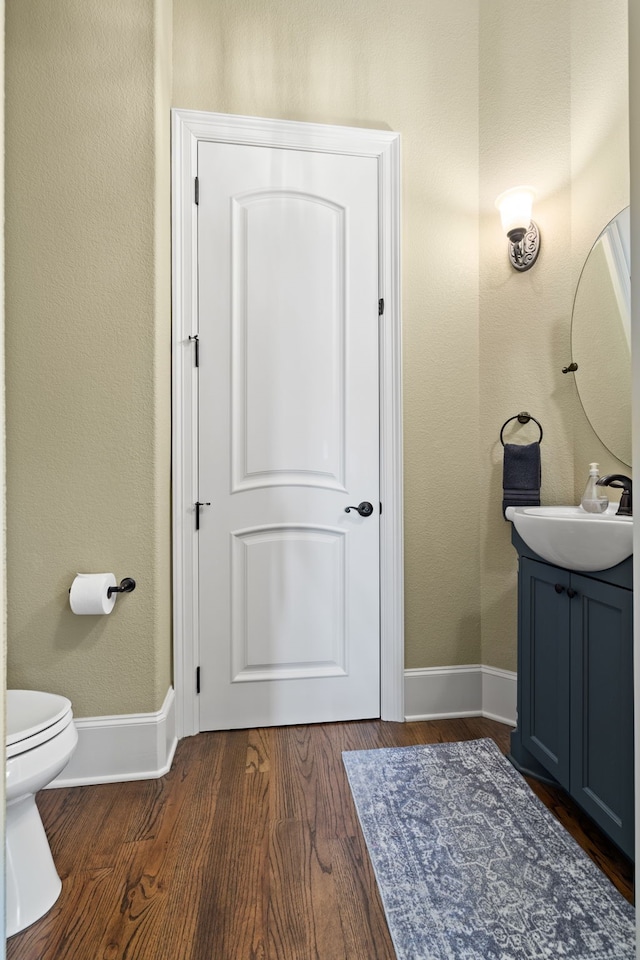 bathroom featuring toilet, vanity, and hardwood / wood-style flooring