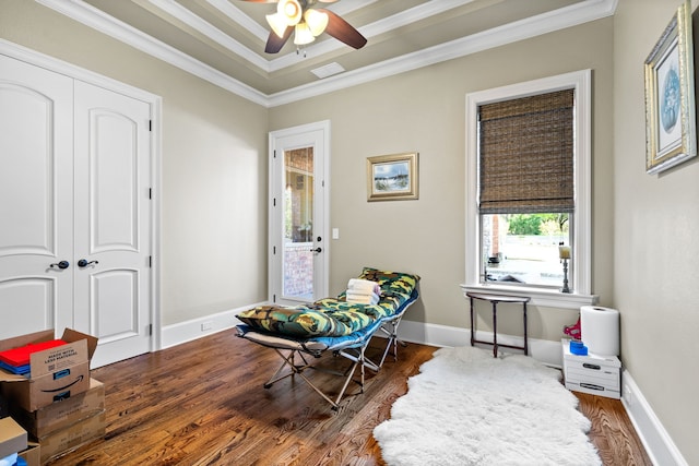 living area featuring dark hardwood / wood-style flooring, ceiling fan, a tray ceiling, and crown molding