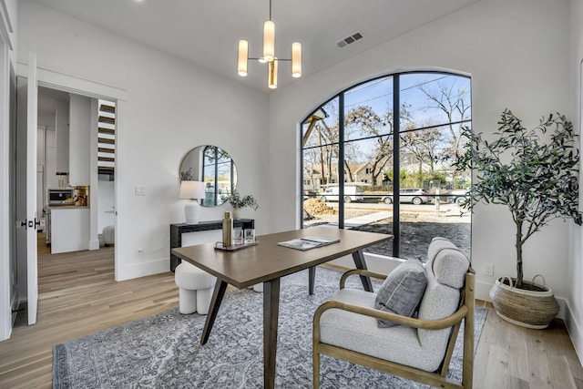 home office with light hardwood / wood-style floors and a chandelier