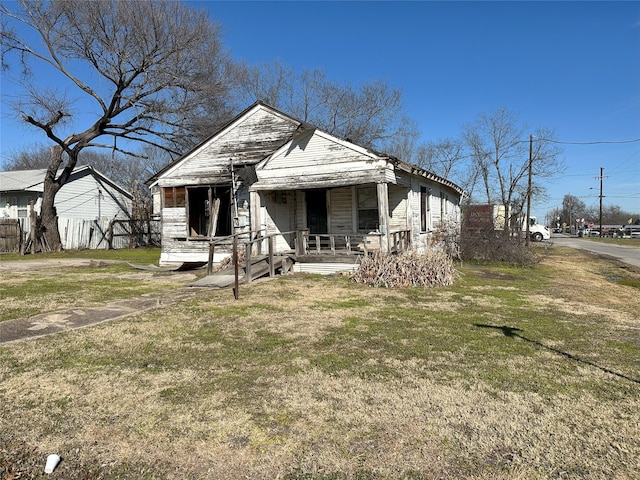 bungalow-style home with a front yard and covered porch