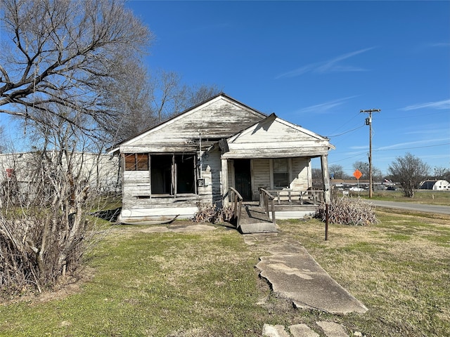 bungalow with covered porch and a front lawn