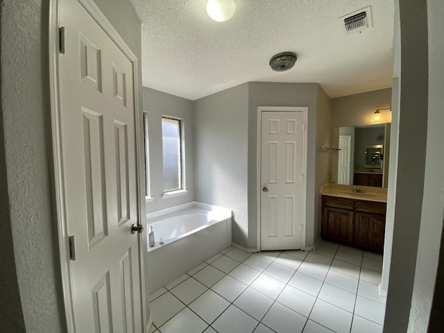 bathroom featuring a textured ceiling, a washtub, tile patterned floors, and vanity