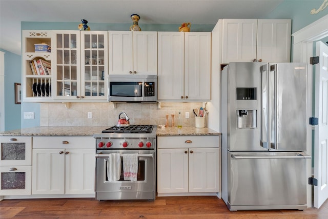 kitchen with light stone countertops, appliances with stainless steel finishes, backsplash, and white cabinetry