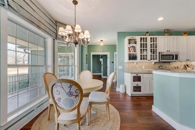 dining room with a healthy amount of sunlight, dark hardwood / wood-style flooring, and a chandelier