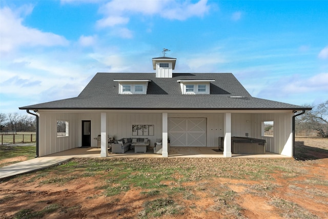 back of property with a hot tub, a patio, and outdoor lounge area