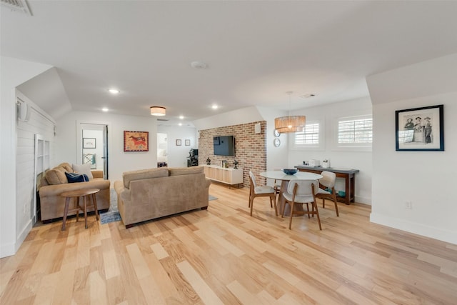 living room with a large fireplace, vaulted ceiling, and light hardwood / wood-style flooring