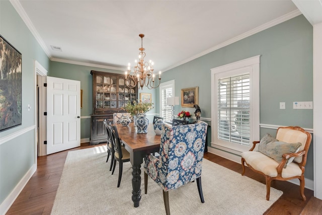 dining space with dark hardwood / wood-style flooring, a chandelier, and ornamental molding