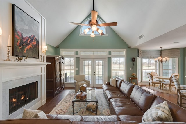 living room with dark wood-type flooring, french doors, vaulted ceiling, and a high end fireplace