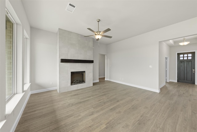 unfurnished living room featuring ceiling fan, hardwood / wood-style floors, and a tile fireplace