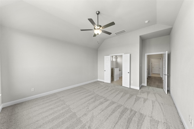 unfurnished bedroom featuring ceiling fan, light colored carpet, connected bathroom, and vaulted ceiling