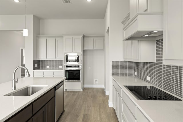 kitchen featuring stainless steel appliances, sink, white cabinetry, light hardwood / wood-style flooring, and hanging light fixtures