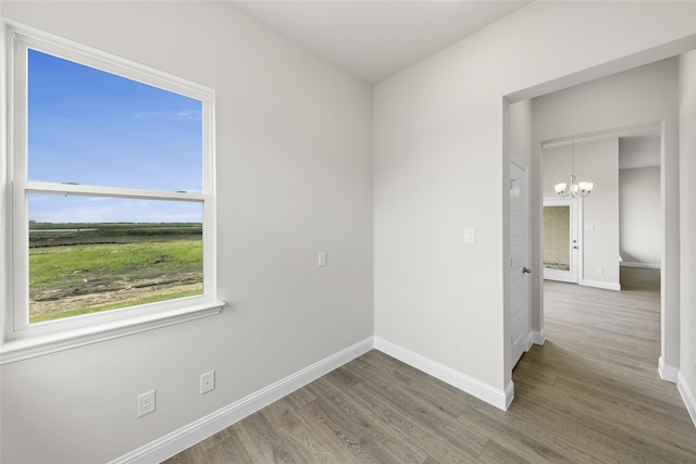 spare room with hardwood / wood-style floors and an inviting chandelier