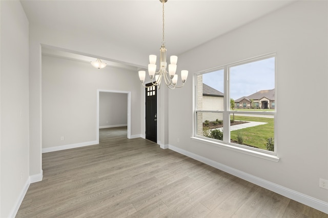 unfurnished dining area with light wood-type flooring and a chandelier