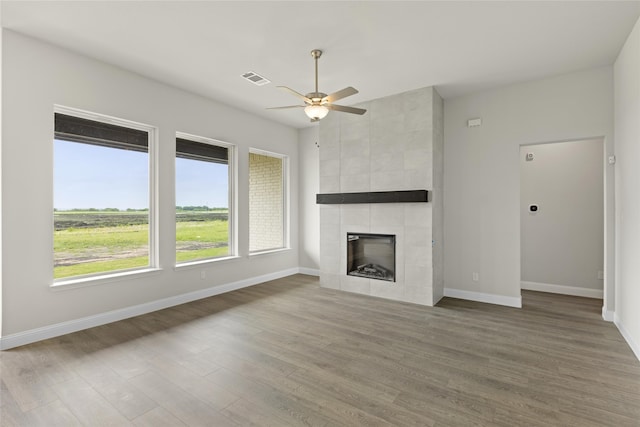 unfurnished living room featuring a tile fireplace, ceiling fan, and hardwood / wood-style flooring