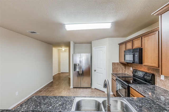 kitchen featuring tasteful backsplash, dark stone countertops, black appliances, sink, and a textured ceiling