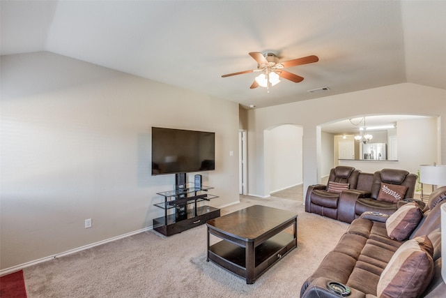 living room featuring light colored carpet, vaulted ceiling, and ceiling fan with notable chandelier