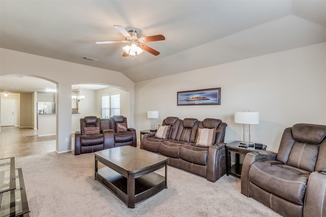 carpeted living room featuring vaulted ceiling and ceiling fan with notable chandelier