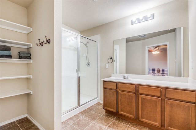 bathroom featuring ceiling fan, vanity, a shower with door, and a textured ceiling