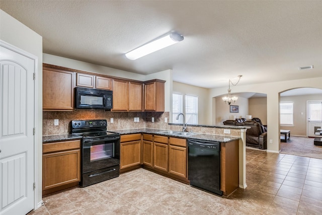 kitchen featuring sink, black appliances, a notable chandelier, and a healthy amount of sunlight