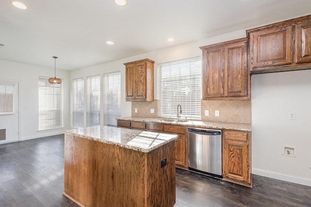 kitchen with pendant lighting, dishwasher, sink, light stone countertops, and a healthy amount of sunlight