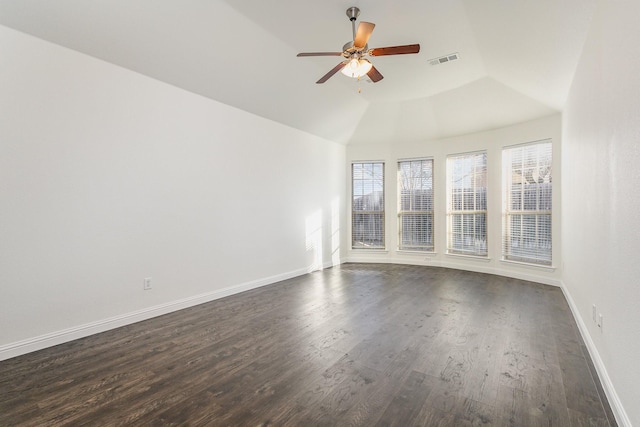 empty room with dark hardwood / wood-style flooring, vaulted ceiling, and ceiling fan