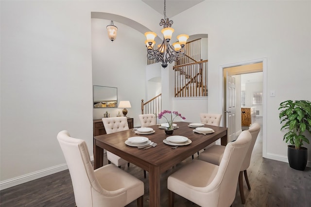 dining space with dark wood-type flooring, high vaulted ceiling, and an inviting chandelier