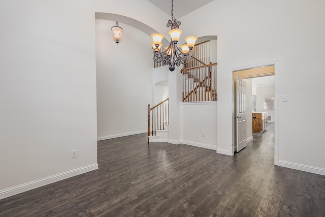 interior space featuring high vaulted ceiling, dark wood-type flooring, and an inviting chandelier