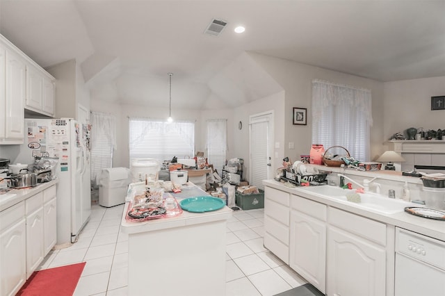 kitchen featuring white refrigerator with ice dispenser, a center island, white cabinets, light tile patterned flooring, and sink