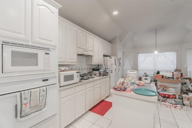 kitchen featuring white appliances, vaulted ceiling, hanging light fixtures, and white cabinetry