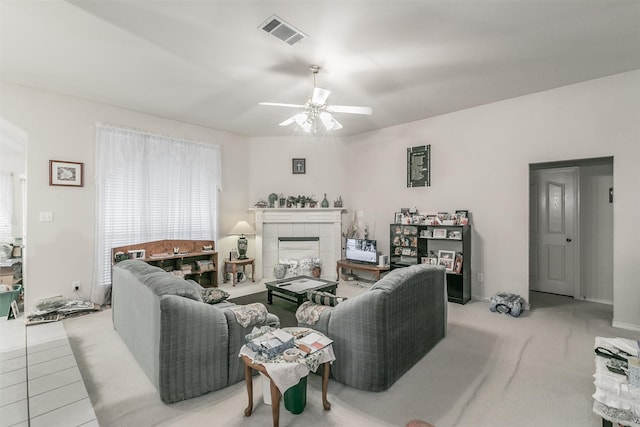 living room with a tile fireplace and ceiling fan