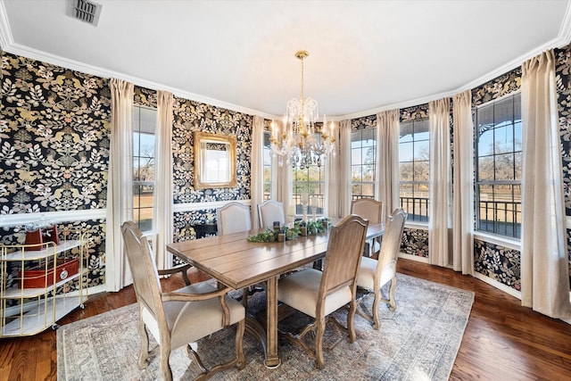 dining space with dark hardwood / wood-style flooring, crown molding, and an inviting chandelier