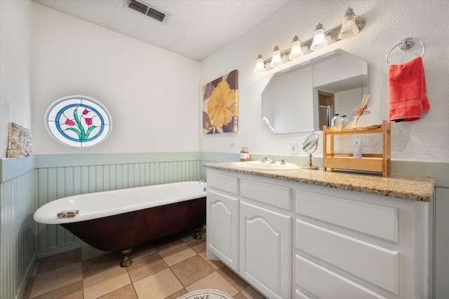 bathroom featuring a textured ceiling, tile patterned floors, a tub, and vanity